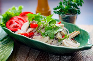 Baharatlı Vietnam sosisi salatası yaprak şeklindeki yeşil tabağa konur. Tayland 'da siyah ahşap bir masada soğan, sarımsak, kırmızı biber.