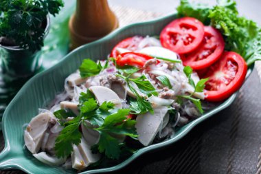 Baharatlı Vietnam sosisi salatası yaprak şeklindeki yeşil tabağa konur. Tayland 'da siyah ahşap bir masada soğan, sarımsak, kırmızı biber.