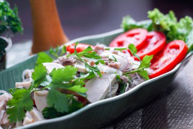 Baharatlı Vietnam sosisi salatası yaprak şeklindeki yeşil tabağa konur. Tayland 'da siyah ahşap bir masada soğan, sarımsak, kırmızı biber.