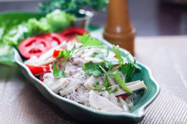 Baharatlı Vietnam sosisi salatası yaprak şeklindeki yeşil tabağa konur. Tayland 'da siyah ahşap bir masada soğan, sarımsak, kırmızı biber.