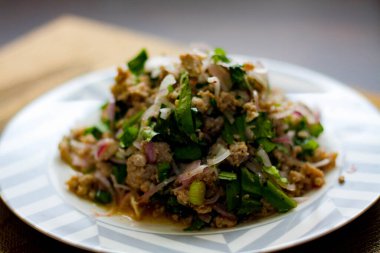 Tayland 'da siyah ahşap bir masaya beyaz ve gri tabaklara soğan, sarımsak ve kırmızı biber konmuş domuz salatası..