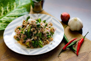 Tayland 'da siyah ahşap bir masaya beyaz ve gri tabaklara soğan, sarımsak ve kırmızı biber konmuş domuz salatası..