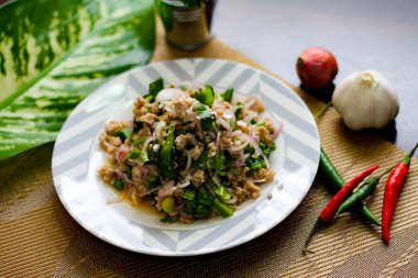 Tayland 'da siyah ahşap bir masaya beyaz ve gri tabaklara soğan, sarımsak ve kırmızı biber konmuş domuz salatası..
