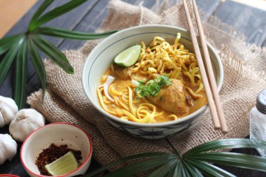 Khao Soi Recipe, Khao Soi, Khao Soi Kai, Thai Noodles Khao Soi, Ahşap masada servis edilen baharatlı Tavuk Köri.