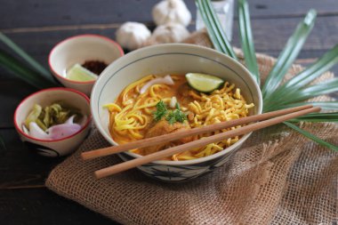 Khao Soi Recipe, Khao Soi, Khao Soi Kai, Thai Noodles Khao Soi, Ahşap masada servis edilen baharatlı Tavuk Köri.