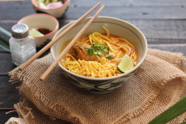 Khao Soi Recipe, Khao Soi, Khao Soi Kai, Thai Noodles Khao Soi, Ahşap masada servis edilen baharatlı Tavuk Köri.