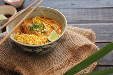 Khao Soi Recipe, Khao Soi, Khao Soi Kai, Thai Noodles Khao Soi, Ahşap masada servis edilen baharatlı Tavuk Köri.