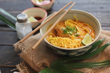 Khao Soi Recipe, Khao Soi, Khao Soi Kai, Thai Noodles Khao Soi, Ahşap masada servis edilen baharatlı Tavuk Köri.