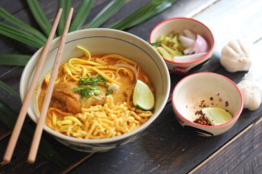 Khao Soi Recipe, Khao Soi, Khao Soi Kai, Thai Noodles Khao Soi, Ahşap masada servis edilen baharatlı Tavuk Köri.