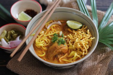 Khao Soi Recipe, Khao Soi, Khao Soi Kai, Thai Noodles Khao Soi, Ahşap masada servis edilen baharatlı Tavuk Köri.