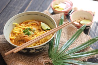 Khao Soi Recipe, Khao Soi, Khao Soi Kai, Thai Noodles Khao Soi, Ahşap masada servis edilen baharatlı Tavuk Köri.
