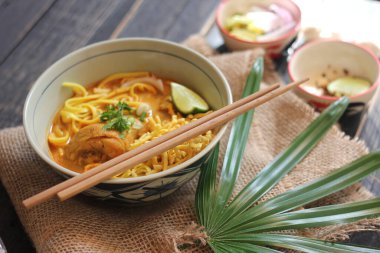 Khao Soi Recipe, Khao Soi, Khao Soi Kai, Thai Noodles Khao Soi, Ahşap masada servis edilen baharatlı Tavuk Köri.