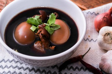 Ahşap bir masada servis edilen beyaz bardakta haşlanmış yumurtalar. Asya 'da yemek.