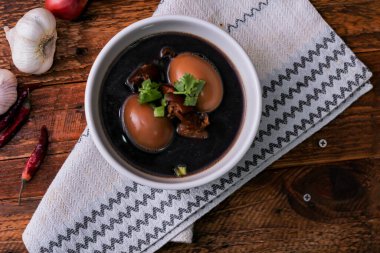 Ahşap bir masada servis edilen beyaz bardakta haşlanmış yumurtalar. Asya 'da yemek.