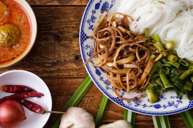 Fıstık soslu Tayland pilavı, ahşap bir masada servis edilir ve yapraklarla süslenir..