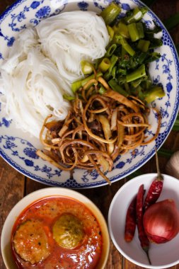 Fıstık soslu Tayland pilavı, ahşap bir masada servis edilir ve yapraklarla süslenir..