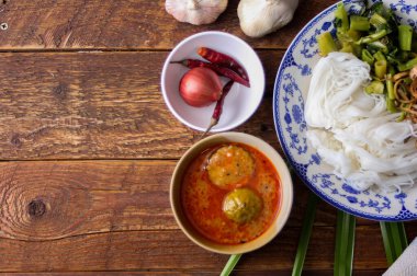 Fıstık soslu Tayland pilavı, ahşap bir masada servis edilir ve yapraklarla süslenir..