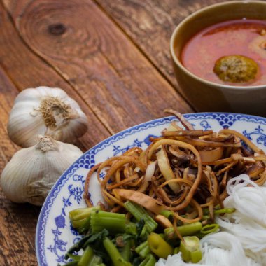 Fıstık soslu Tayland pilavı, ahşap bir masada servis edilir ve yapraklarla süslenir..