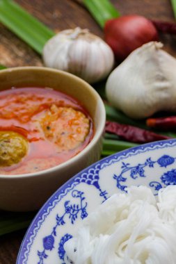 Fıstık soslu Tayland pilavı, ahşap bir masada servis edilir ve yapraklarla süslenir..