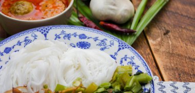 Fıstık soslu Tayland pilavı, ahşap bir masada servis edilir ve yapraklarla süslenir..