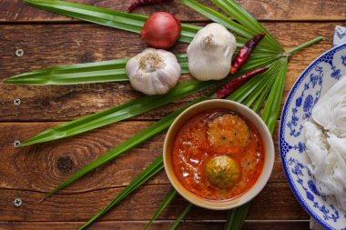Fıstık soslu Tayland pilavı, ahşap bir masada servis edilir ve yapraklarla süslenir..
