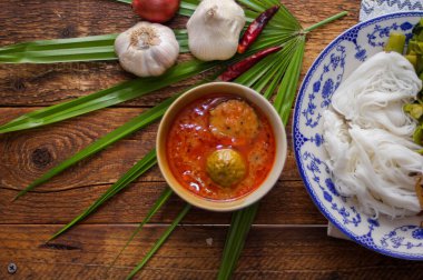 Fıstık soslu Tayland pilavı, ahşap bir masada servis edilir ve yapraklarla süslenir..