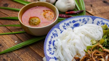 Fıstık soslu Tayland pilavı, ahşap bir masada servis edilir ve yapraklarla süslenir..