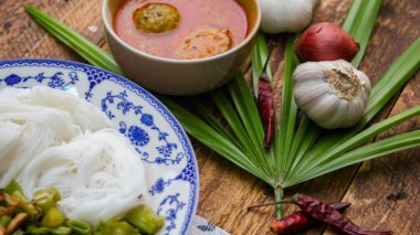 Fıstık soslu Tayland pilavı, ahşap bir masada servis edilir ve yapraklarla süslenir..
