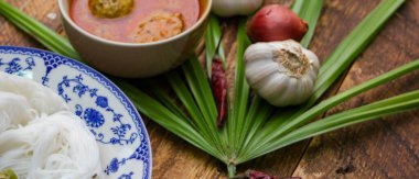 Fıstık soslu Tayland pilavı, ahşap bir masada servis edilir ve yapraklarla süslenir..