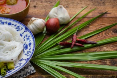 Fıstık soslu Tayland pilavı, ahşap bir masada servis edilir ve yapraklarla süslenir..