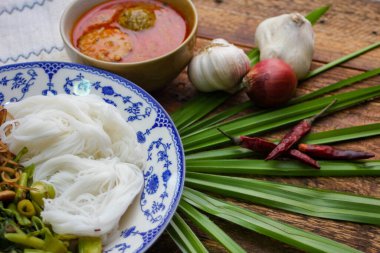 Fıstık soslu Tayland pilavı, ahşap bir masada servis edilir ve yapraklarla süslenir..