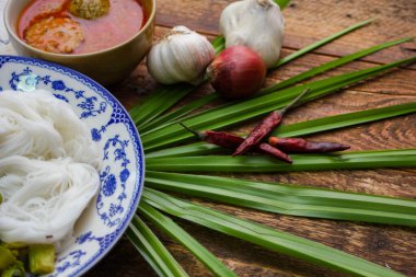Fıstık soslu Tayland pilavı, ahşap bir masada servis edilir ve yapraklarla süslenir..