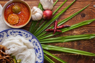 Fıstık soslu Tayland pilavı, ahşap bir masada servis edilir ve yapraklarla süslenir..