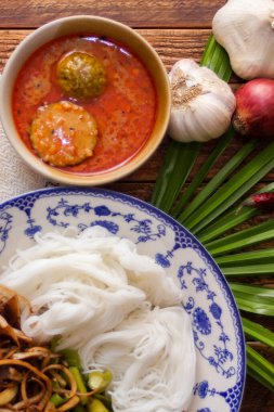 Fıstık soslu Tayland pilavı, ahşap bir masada servis edilir ve yapraklarla süslenir..