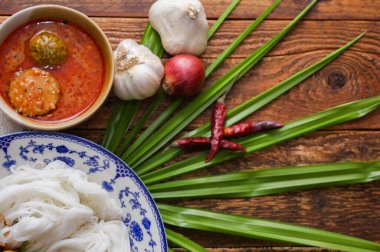 Fıstık soslu Tayland pilavı, ahşap bir masada servis edilir ve yapraklarla süslenir..