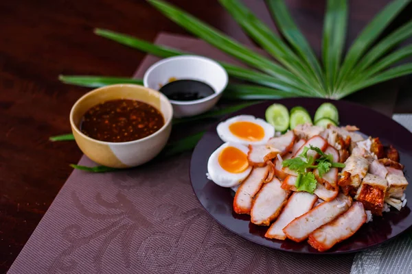 蒸饭和红肉 脆猪肉在一个黑色盘子里 蘸着酱油和深色酱油 放在一个黑色木制桌子上 亚洲的食物 — 图库照片