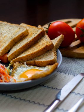 Kahvaltı, sahanda yumurta, kızarmış sosis, sebze salatası ve kahverengi ahşap bir masada tost ve Tayland kahvesi..