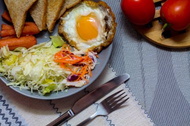 Kahvaltı, sahanda yumurta, kızarmış sosis, sebze salatası ve kahverengi ahşap bir masada tost ve Tayland kahvesi..