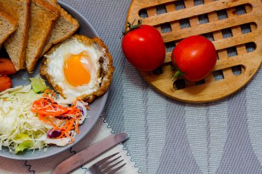 Kahvaltı, sahanda yumurta, kızarmış sosis, sebze salatası ve kahverengi ahşap bir masada tost ve Tayland kahvesi..