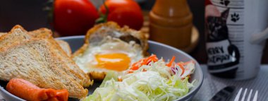 Kahvaltı, sahanda yumurta, kızarmış sosis, sebze salatası ve kahverengi ahşap bir masada tost ve Tayland kahvesi..