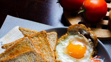 Kahvaltı, sahanda yumurta, kızarmış sosis, sebze salatası ve kahverengi ahşap bir masada tost ve Tayland kahvesi..
