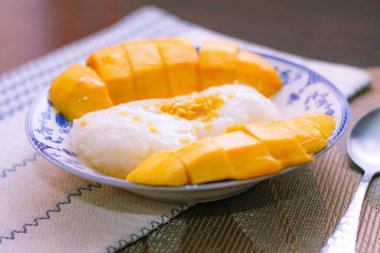 Hindistan cevizi sütü ve soya fasulyesiyle kaplanmış mangolu pirinç Tayland 'da ahşap bir masada geleneksel Çin usulü bir yemeğe konur..