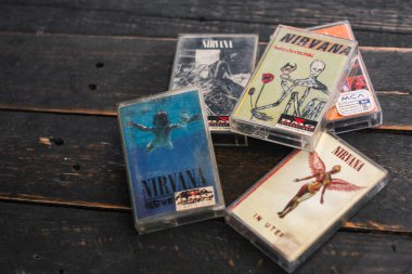 Bangkok, Tayland - 22 Ocak 2022: 90: Nirvana Albums Incesticide, Nevermind, Bleach, The Muddy Banks of The Wishkah 'ın siyah ahşap zemin üzerindeki kasetleri.