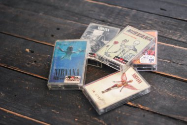 Bangkok, Tayland - 22 Ocak 2022: 90: Nirvana Albums Incesticide, Nevermind, Bleach, The Muddy Banks of The Wishkah 'ın siyah ahşap zemin üzerindeki kasetleri.