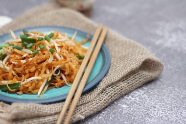 Tayland yemeği Pad Thai Thai kızarmış eriştesi (ulusal yemek) mavi tabakta servis edilir..
