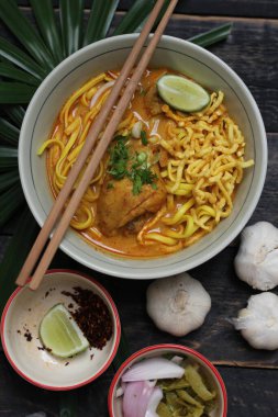 Khao Soi Recipe, Khao Soi, Khao Soi Kai, Thai Noodles Khao Soi, Ahşap masada servis edilen baharatlı Tavuk Köri.