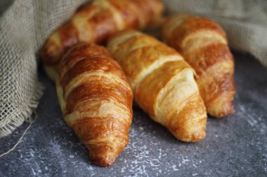 Tahta tabaklar ve çuval bezle masaya istiflenmiş kruvasan ekmeği..