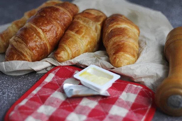 灰色のテーブルの上にバターを添えておいしい新鮮なクロワッサンの山 — ストック写真