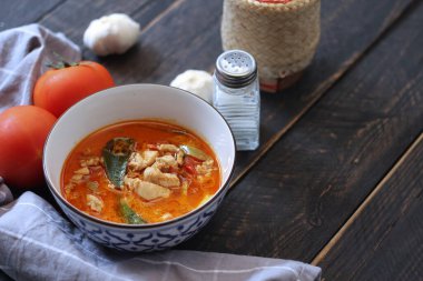 Tayland usulü bir tabakta siyah ahşap bir masada servis edilen tavuk pananjiri..