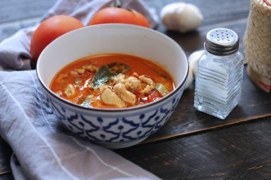 Tayland usulü bir tabakta siyah ahşap bir masada servis edilen tavuk pananjiri..